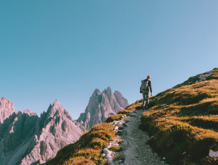 Hiker Climbing A Mountain With Blue Sky In The Background