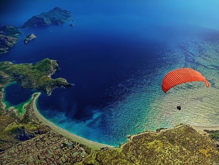 A Man Paragliding With Sea And Coastal City Seen Underneath