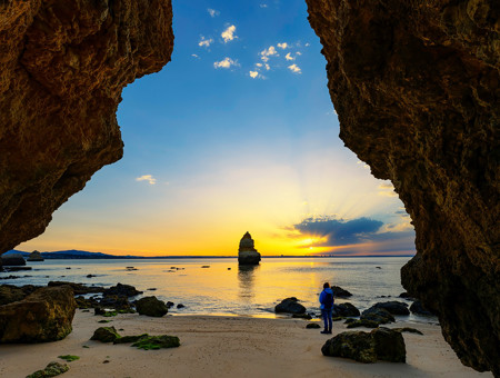  A Person Standing Next To A Sea With Cliffs By The Sides