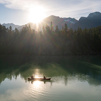 Two People Rafting With Mountains And Forest Behind