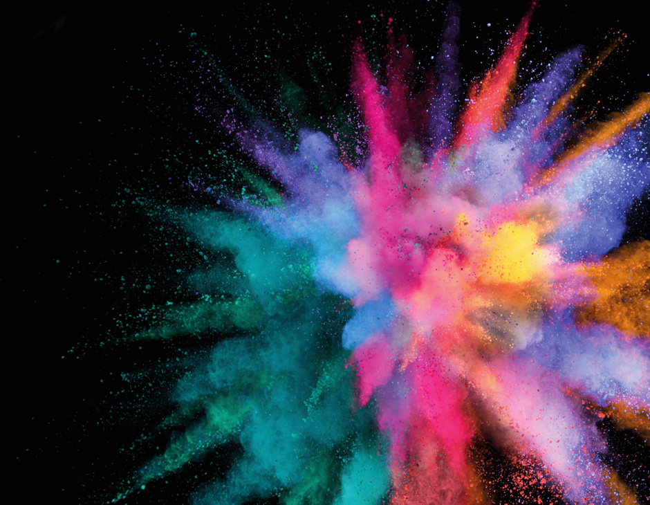 An explosion of colour - a dust cloud of colour is exploding with pinks, greens, blues, orange and yellow on a black background