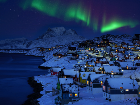  A Picturesque Seaside Village With Snow Covered Rooftops, Set Against A Stunning Backdrop Of Vibrant Northern Lights Illuminating The Night Sky