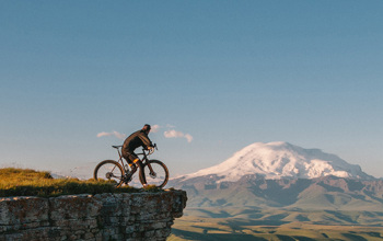  Cyclist At The Ledge Of A Mountain Looking At The Skyline